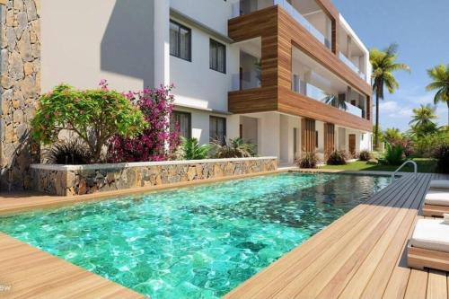 a swimming pool in front of a house at Joli appartement neuf 2ch 2sdb 50m de la mer in Grand-Baie