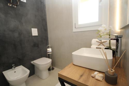 a bathroom with a white sink and a toilet at Ohana Holiday Rooms in Rosolina Mare