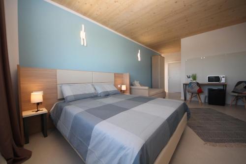 1 dormitorio con 1 cama grande y techo de madera en Ohana Holiday Rooms, en Rosolina Mare