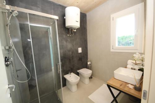 a bathroom with a shower and a toilet and a sink at Ohana Holiday Rooms in Rosolina Mare