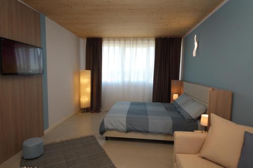 a bedroom with a bed and a tv and a couch at Ohana Holiday Rooms in Rosolina Mare