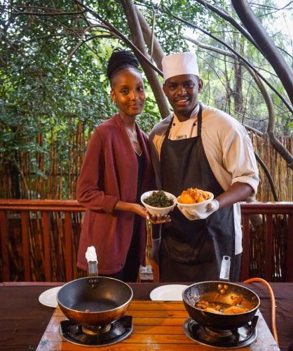 a man and woman standing next to a table with food at Heaven Restaurant & Boutique Hotel in Kigali