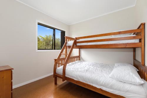 a bedroom with two bunk beds and a window at Pipi Cabin - Mangawhai Village Bach in Mangawhai