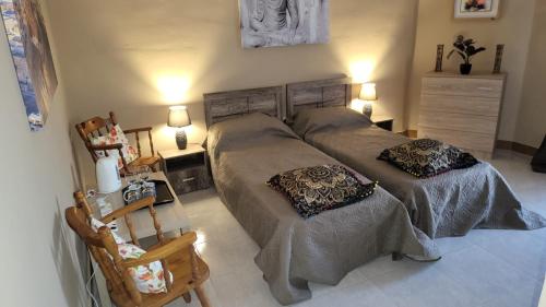 a bedroom with two beds and a chair at Lotus Apartment in Tad-Duluri