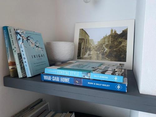 ein Regal mit Büchern und einem Bild darauf in der Unterkunft Shrimp Cottage - 3 bed renovated cottage with stunning sea views in Staithes