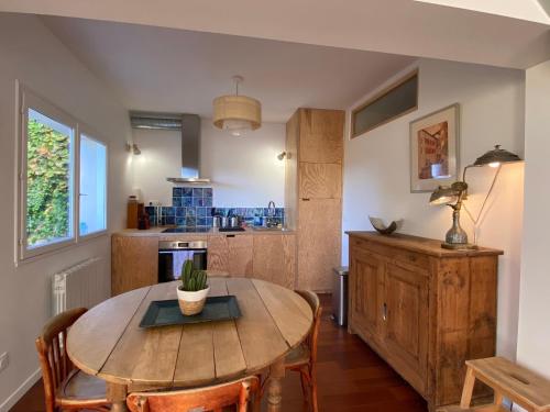 - une cuisine avec une table en bois, des chaises et une table dans l'établissement Maison de charme avec jardin et terrasse, à Camblanes-et-Meynac