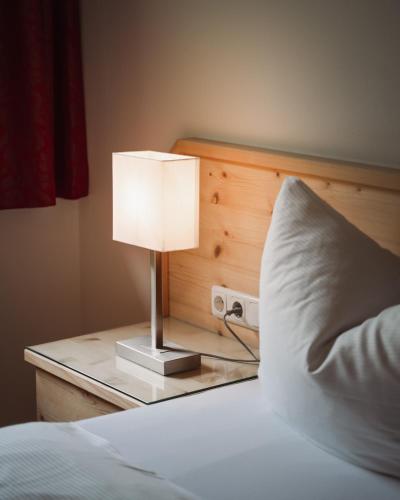a bed with a lamp on a table with a pillow at Appartementhaus Zum Schneider in Scheffau am Wilden Kaiser