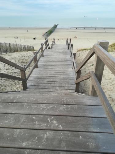 a wooden boardwalk leading to a beach with people at Bartine - modern and spacious flat near the sea, free parking space in Ostend
