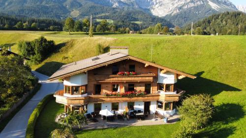 a house in a field with mountains in the background at Appartementhaus Zum Schneider in Scheffau am Wilden Kaiser
