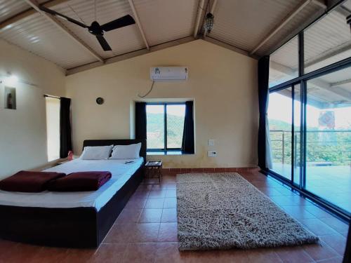 um quarto com uma cama grande e uma janela grande em Aashraay Bungalow em Kārle