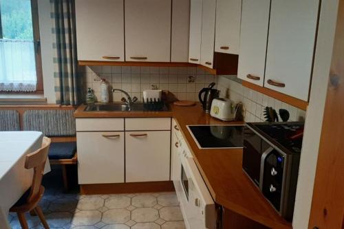 a kitchen with white cabinets and a sink and a stove at Alpine cottage with exceptional view in Mayrhofen