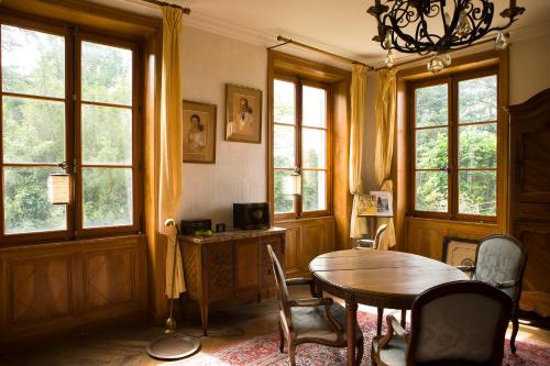 comedor con mesa, sillas y ventanas en Le Montellier, en Blacé