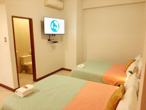 Cette chambre comprend 2 lits et une télévision murale. dans l'établissement 100 RV Apartments Iquitos-Apartamento primer piso con vista a piscina, à Iquitos