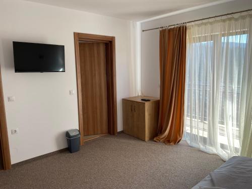 - une chambre avec un lit, une télévision et une fenêtre dans l'établissement Pensiunea Joe Paltinis, à Păltiniş