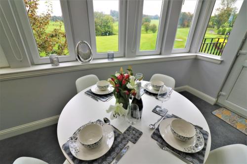 a dining room with a white table and chairs and windows at Signature - Greenlees Clubhouse in Glasgow