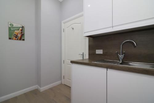 a kitchen with white cabinets and a sink at Signature - Greenlees Clubhouse in Glasgow