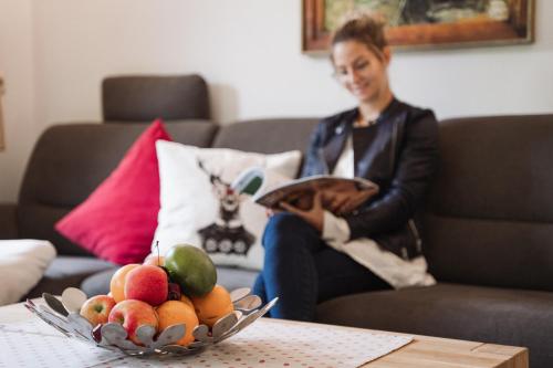 a woman sitting on a couch with a bowl of fruit at Appartementhaus Zum Schneider in Scheffau am Wilden Kaiser