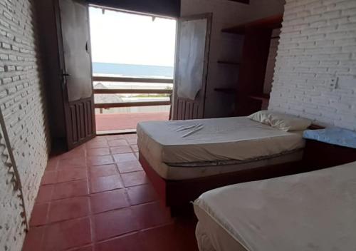 1 dormitorio con 2 camas y ventana grande en CASA DE PRAIA (PE NA AREIA), en Caponga