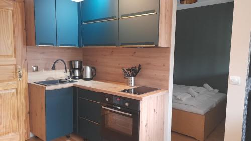 a small kitchen with blue cabinets and a bed at Auszeit auf Insel Usedom in Garz-Usedom