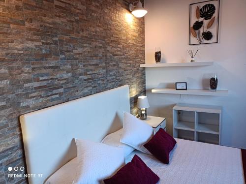 a bedroom with a white bed with a brick wall at Ele House in Tarajalejo