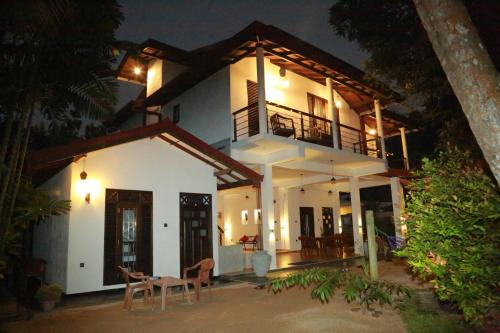 uma grande casa branca com uma varanda à noite em Midigama Holiday Inn em Midigama East
