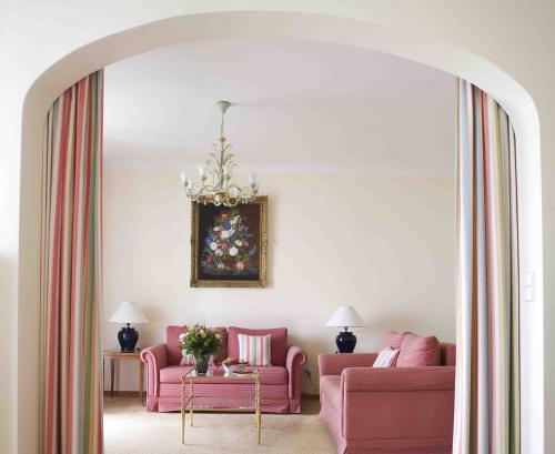 a living room with two pink couches and a table at Hotel Bad Schachen in Lindau
