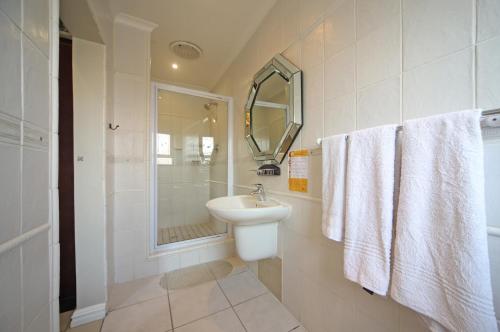 a white bathroom with a sink and a shower at Savoy Lodge in Cape Town