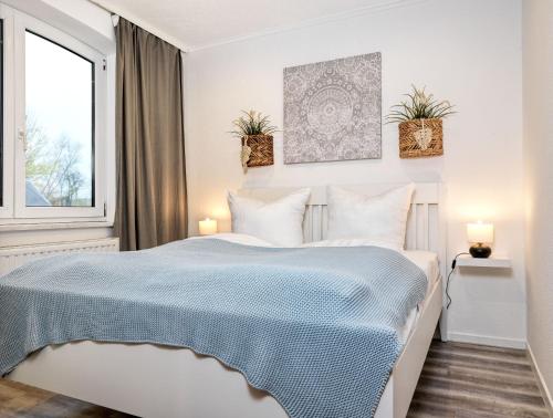 ein weißes Schlafzimmer mit einem Bett mit einer blauen Decke in der Unterkunft Ferienanlage Poschmann Fischerstube in Insel Poel