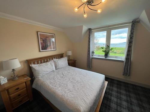 ein Schlafzimmer mit einem Bett und einem großen Fenster in der Unterkunft Taigh Mara(Marine House) 2 bed Apartment in Fort William