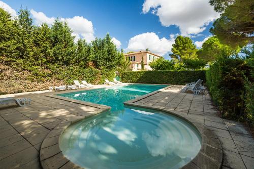 une piscine avec des chaises et une maison en arrière-plan dans l'établissement Pézenas Cottage avec terrasse et jardin 1 chambre et 1 mezzanine au coeur d'un domaine avec 2 piscines, à Alignan-du-Vent