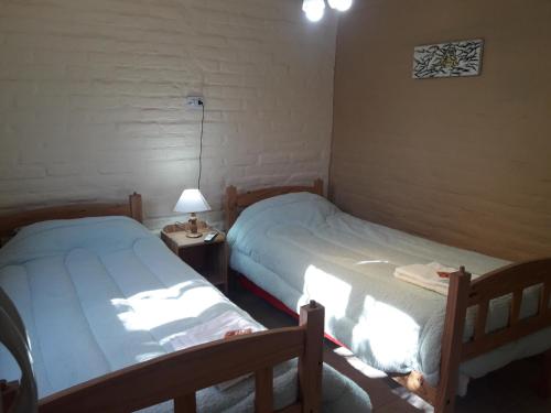 um quarto com duas camas e um candeeiro sobre uma mesa em Finca ELSA em San Agustín de Valle Fértil