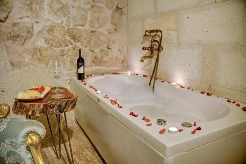 Una bañera blanca en una habitación con una botella de vino en Mahperi Cappadocia Cave en Nevşehir