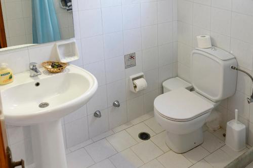 a white bathroom with a toilet and a sink at Elena Studios & Apartments in Piso Livadi