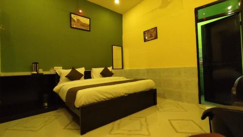 1 dormitorio con 1 cama con paredes verdes y TV en Ranthambore Aravalli, en Sawāi Mādhopur