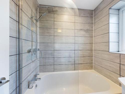 威根的住宿－Stunning Family Home with Comfortable Surroundings，带浴缸和玻璃淋浴间的浴室。