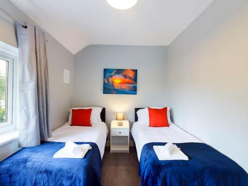 2 Betten in einem Zimmer mit blauen und roten Kissen in der Unterkunft Stunning Family Home with Comfortable Surroundings in Wigan