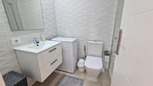 Baño blanco con aseo y lavamanos en Ocean View Apartment, Costa Adeje,Tenerife, en Adeje