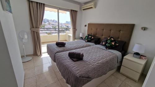 Ocean View Apartment, Costa Adeje,Tenerife في أديخي: غرفة نوم بسريرين ونافذة كبيرة