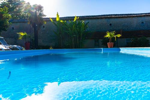 une grande piscine d'eau bleue devant un bâtiment dans l'établissement Logis de Tirac, à Lorignac
