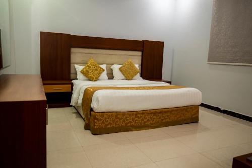 1 dormitorio con 1 cama grande con almohadas de oro en أنوار نجد للشقق الفندقية en Riad