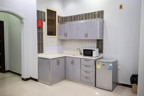 cocina con armarios blancos, fregadero y microondas en أنوار نجد للشقق الفندقية en Riad