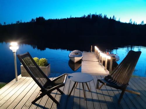 a dock with two chairs and a table and a boat at Villa Rajala in Imatra