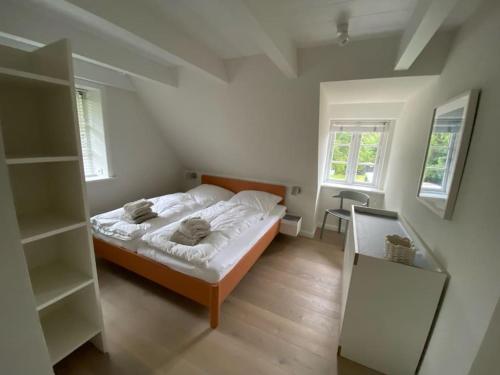 a bedroom with a bed with white sheets and two windows at Wöda in Nieblum