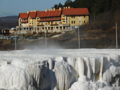 a building in the snow with ice formations at Gyógyvölgy apartman in Egerszalók