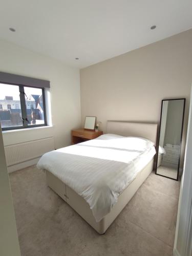 a white bedroom with a large bed and a mirror at City Centre 2 bedrooms 2 Ensuite Flat free parking in Nottingham