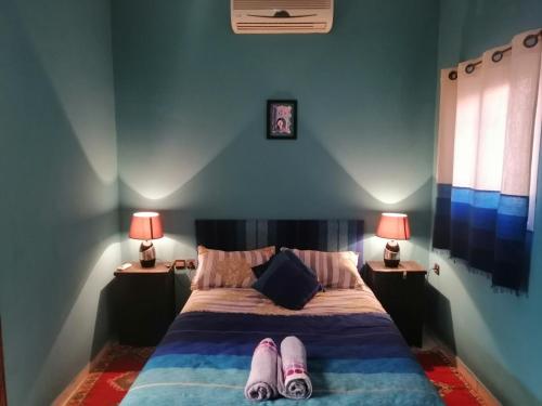 een slaapkamer met een bed met twee lampen en schoenen erop bij Dar Tariq 3 suites avec pisicine in Marrakesh