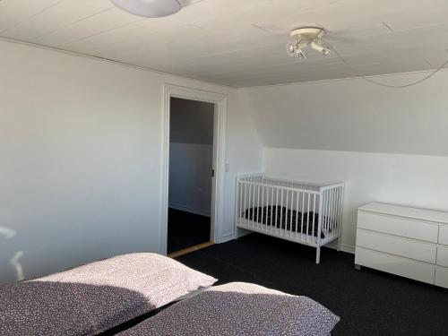 a white bedroom with a crib and a room with a ceiling at Hyggeligt byhus in Harboør