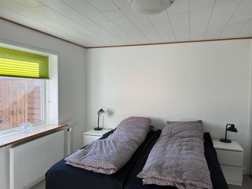 a bedroom with two beds and a window at Hyggeligt byhus in Harboør