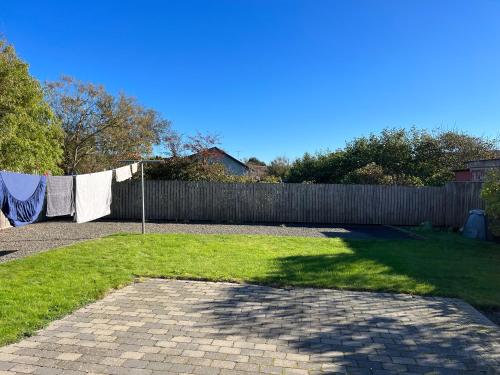 a backyard with a fence and aicked yard with a yard at Hyggeligt byhus in Harboør