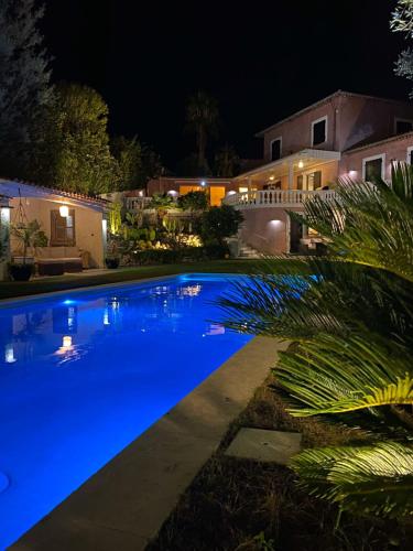 - une piscine bleue la nuit avec une maison dans l'établissement La Dolce Villa 11 sleeps Pool & Landscaped Garden, à Mandelieu-la-Napoule